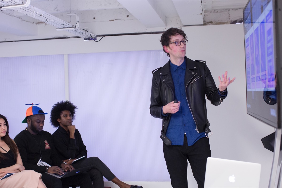 Will speaking at the Guardian Media Summit, with audience members to his left and a large screen to his right