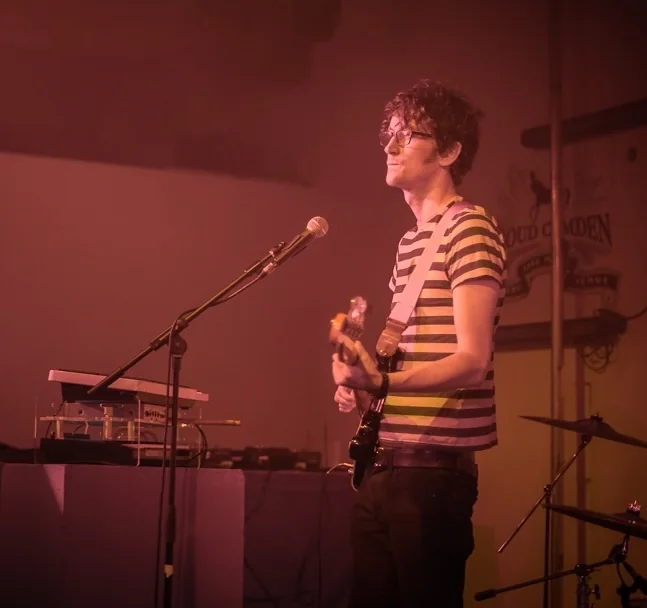 Playing on stage at Proud Camden, under warm red stage lights