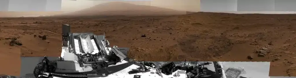 Panoramic view from the Curiosity rover across a rocky Martian landscape.