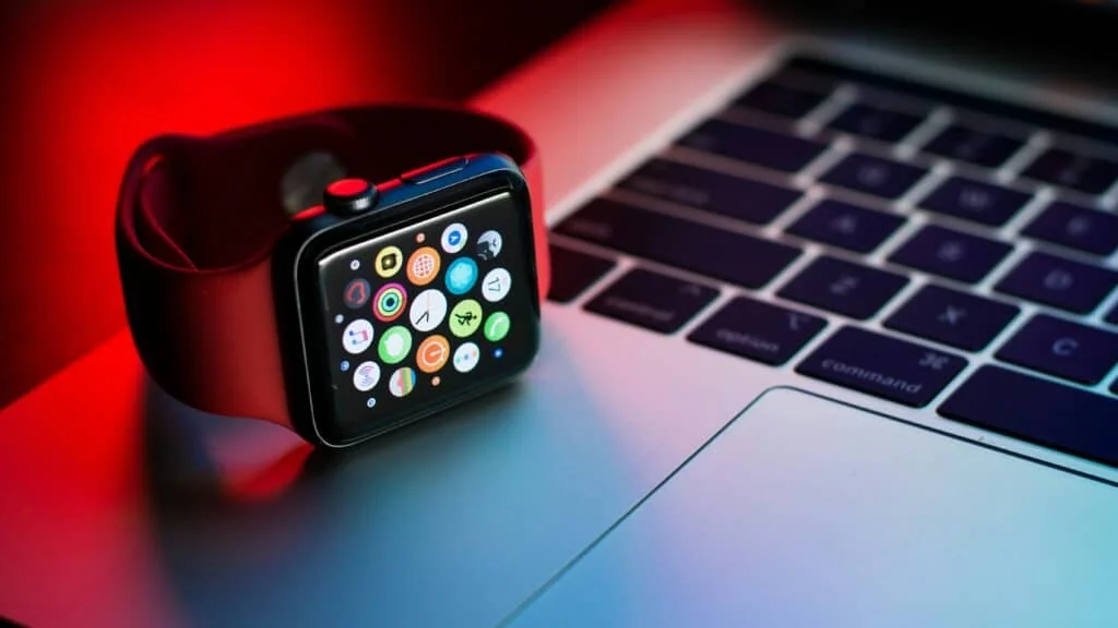 Apple Watch beside a laptop keyboard, with the app grid visible.
