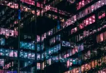 ChatGPT Industry Trends Prompt: Create an Industry Briefing in Minutes City office block windows at night with different colored lighting inside reflecting out off opposing glass walls to create an almost abstract geometric lattice of different colored lights.