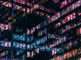 ChatGPT Industry Trends Prompt: Create an Industry Briefing in Minutes City office block windows at night with different colored lighting inside reflecting out off opposing glass walls to create an almost abstract geometric lattice of different colored lights.